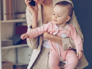 Mom juggling work at home while holding a baby