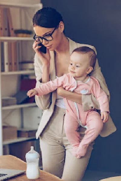 Mom juggling work at home while holding a baby