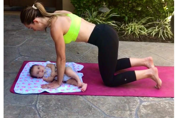 Mom on hands and knees doing an ab exercise with her baby