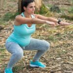 fit pregnant mom squatting in nature
