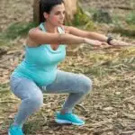 fit pregnant mom squatting in nature