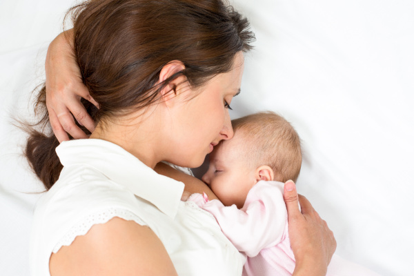 mom laying with her baby breastfeeding her newborn