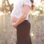 pregnant mom in a black skirt and white top holding her belly