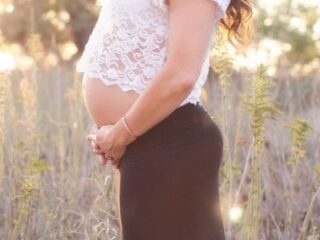 pregnant mom in a black skirt and white top holding her belly
