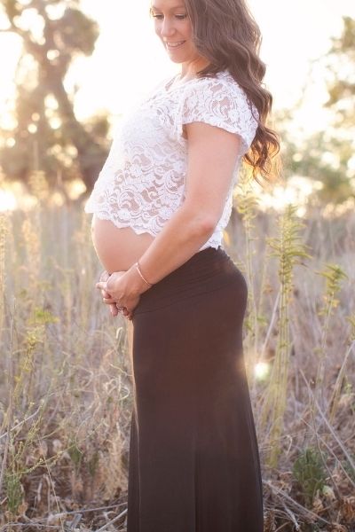 pregnant mom in a black skirt and white top holding her belly