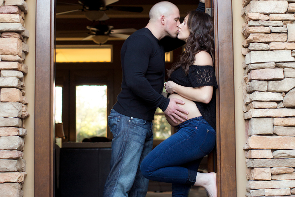 dad kissing pregnant mom with his hand on her belly 