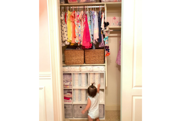 little girl standing in front of her closet that is organized 