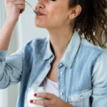 women in blue button up shirt enjoying her food with a spoon