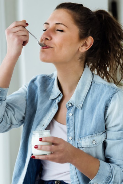 women in blue button up shirt enjoying her food with a spoon