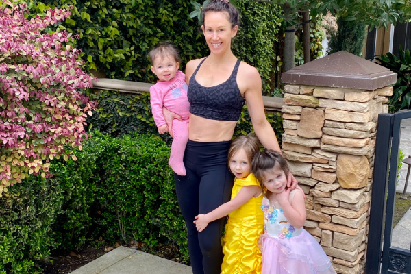 fit mom in black workout clothes taking a picture with her three daughters 