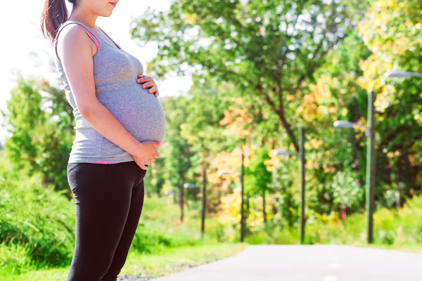 pregnant mom in her last trimester of pregnancy holding her belly before she goes for a run