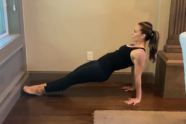 fit postpartum mom wearing all black doing a reverse plank exercise to relieve back pain from breastfeeding