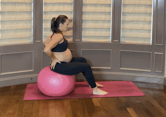 Pregnant mom doing a pelvic tilt exercise on a yoga ball