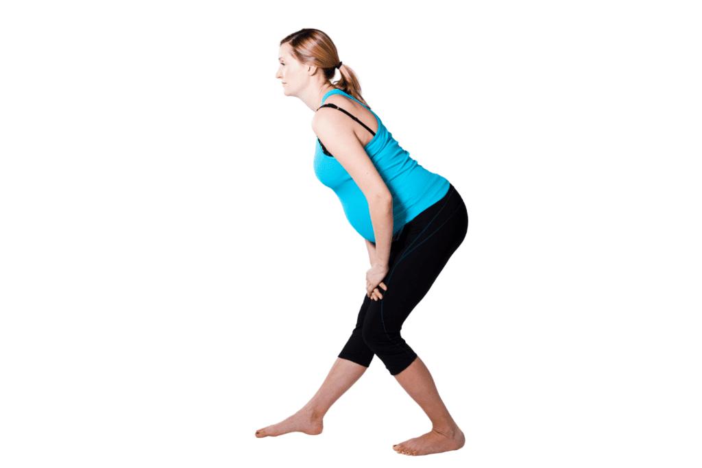 pregnant mom with one foot in front of the other doing a standing hamstring stretch for sciatic pain relief