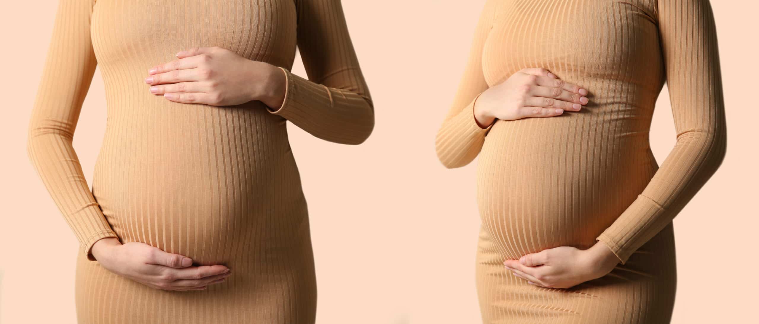 pregnant mom holding her belly with one hand on top and one hand on the bottom. She is wearing a fitted dress with shapewear underneath 